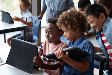 Three children at a charter school looking at tablets together.