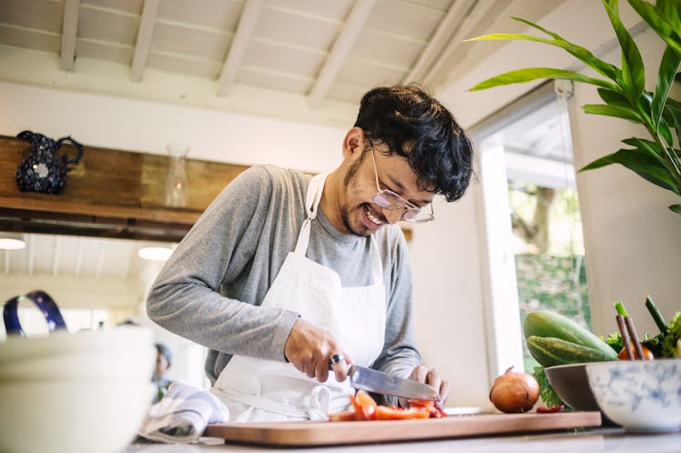 A man chopping vegetables at home.