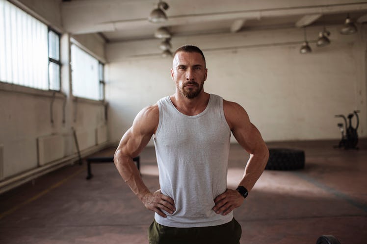 A man in a gym power posing with his hands on his hips.