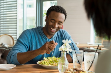A man eating salad at a cafe to increase his HDL cholesterol.