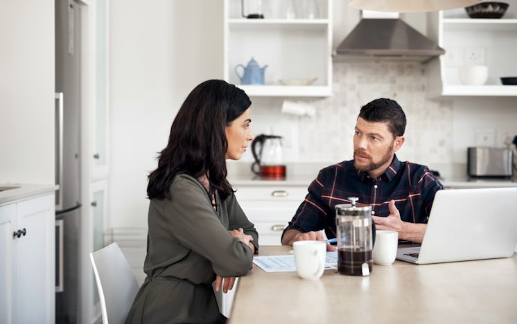 Man and woman sitting at breakfast table having serious conversation