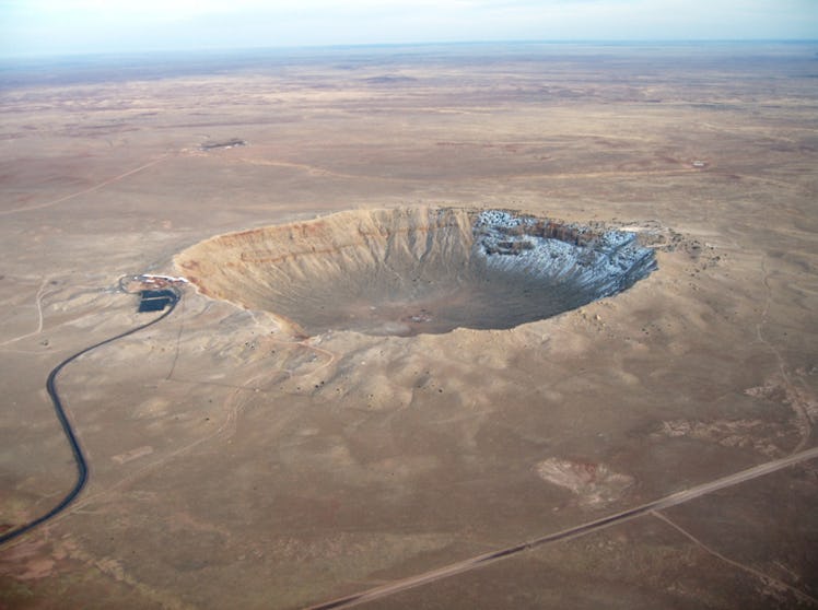 photo of a crater in the desert floor with a road leading to it