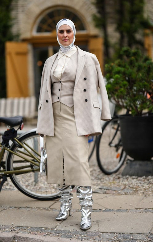 COPENHAGEN, DENMARK - AUGUST 10: A guest wears a white and silver silk scarf as a headband, a beige ...