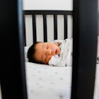 A baby in a sleep sack sleeping in their crib.