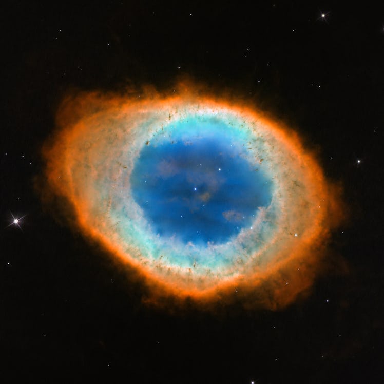 color image of a nebula in space, roughly oval shaped, blue at the center and red at the outer edges