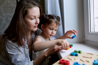 A Kindergarten child with their mother, playing a puzzle game to learn to count.