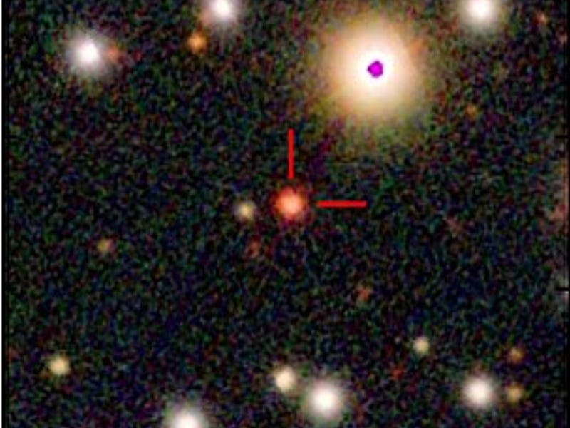 A star field in space, with a central star marked with two red lines at a right angle to each other.