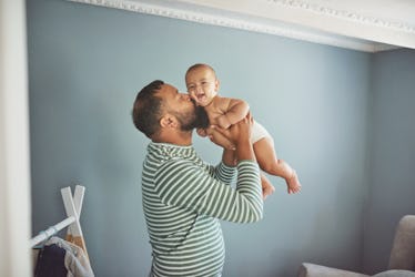 Young dad kissing infant child he holds in his arms