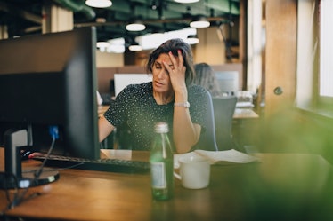 Woman in a corporate job in front of her computer and looking stressed out