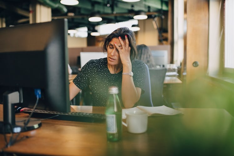 Woman in a corporate job in front of her computer and looking stressed out