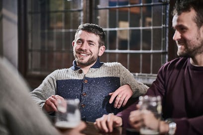 Confident, happy man sitting with friends around a table
