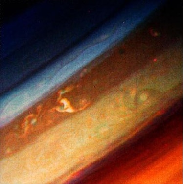Color image of bands of red, orange, brown and white clouds on a gas giant planet