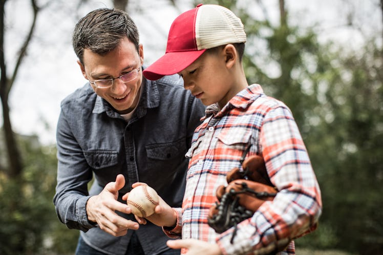 Adult man teaching young boy how to hold a baseball