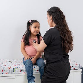An overweight child getting checked out by a nurse in a doctor's office, listening to her heart with...