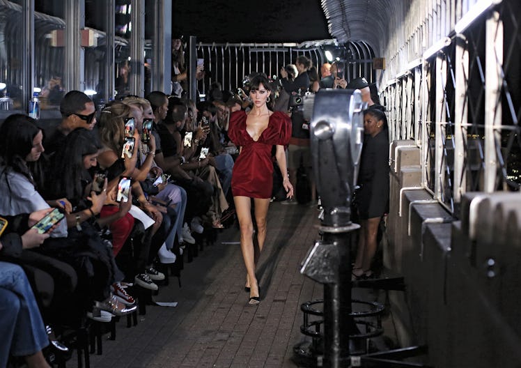  The model wears a red dress as the crowd watches.