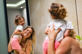 A woman looks in the mirror with her child.