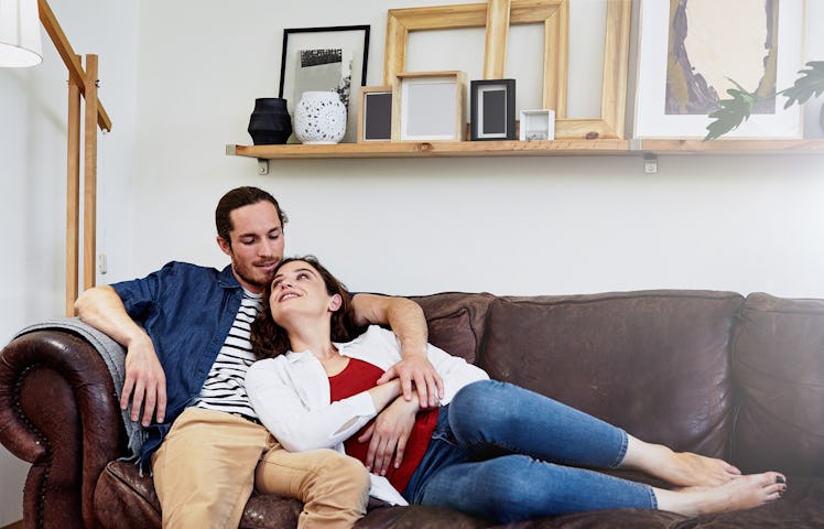 Man listening to woman as she lays on the couch with her head in his lap