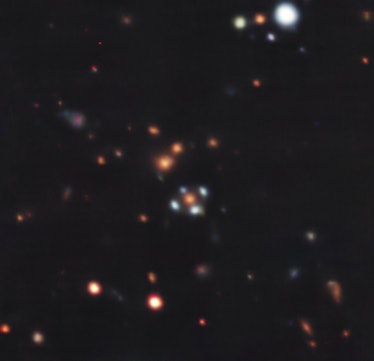 photo of a field of galaxies in space. Near the center is an orange galaxy surrounded by 4 copies of...
