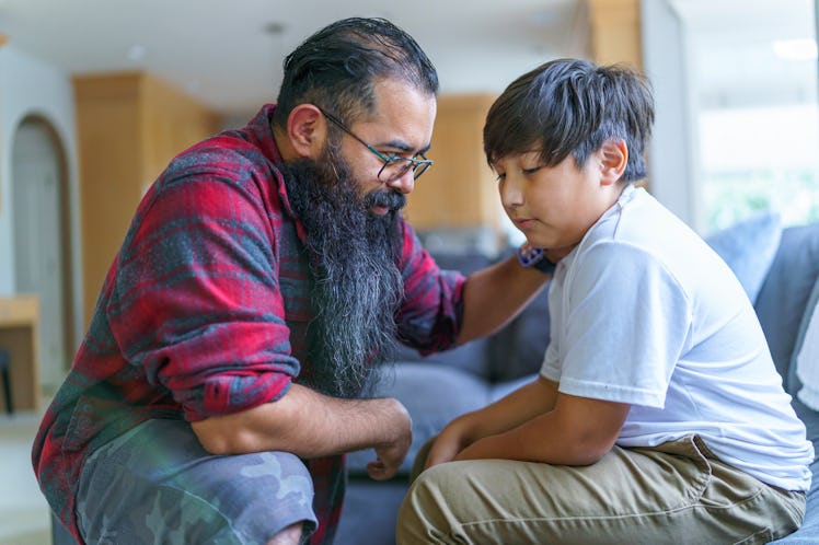 A dad having a serious conversation with his son, putting his hand on his son's shoulder.