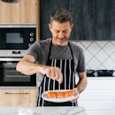A man seasoning salmon before cooking it in his kitchen at home.