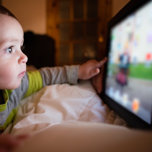 A 1-year-old having screen time by playing a game on a tablet.