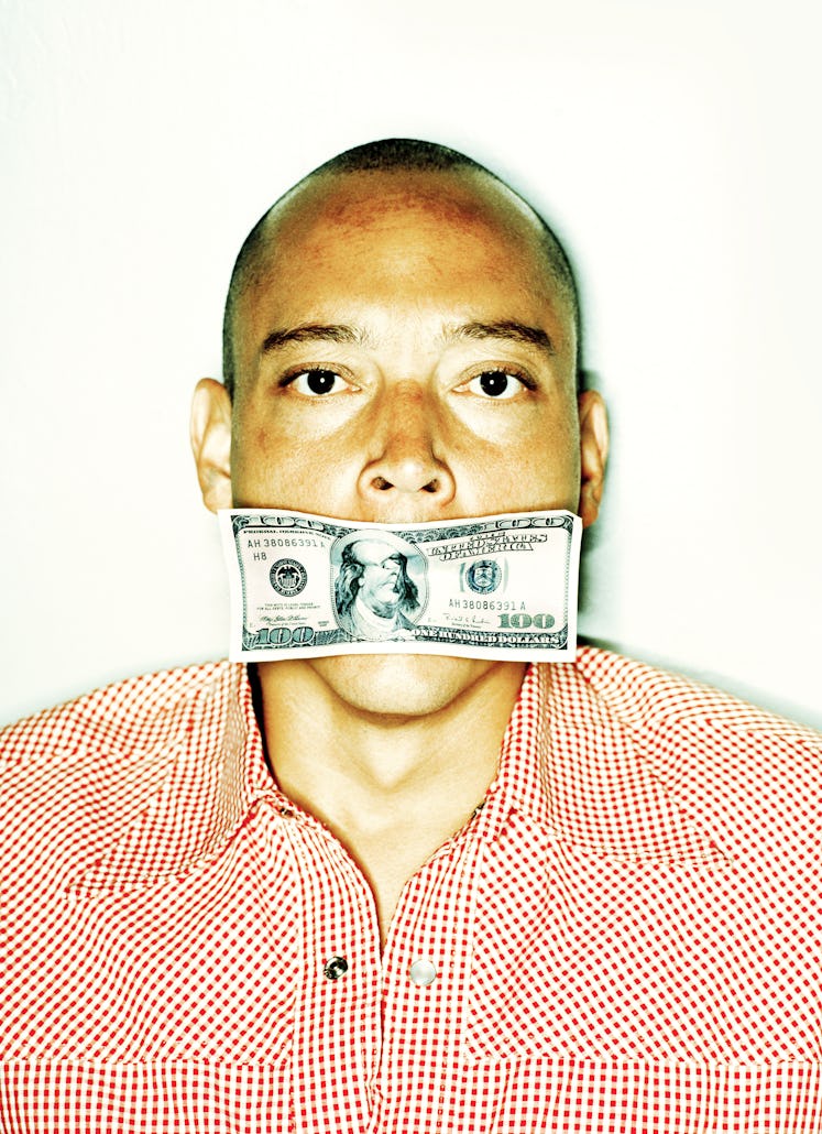 Portrait of man with hundred dollar bill covering his mouth.