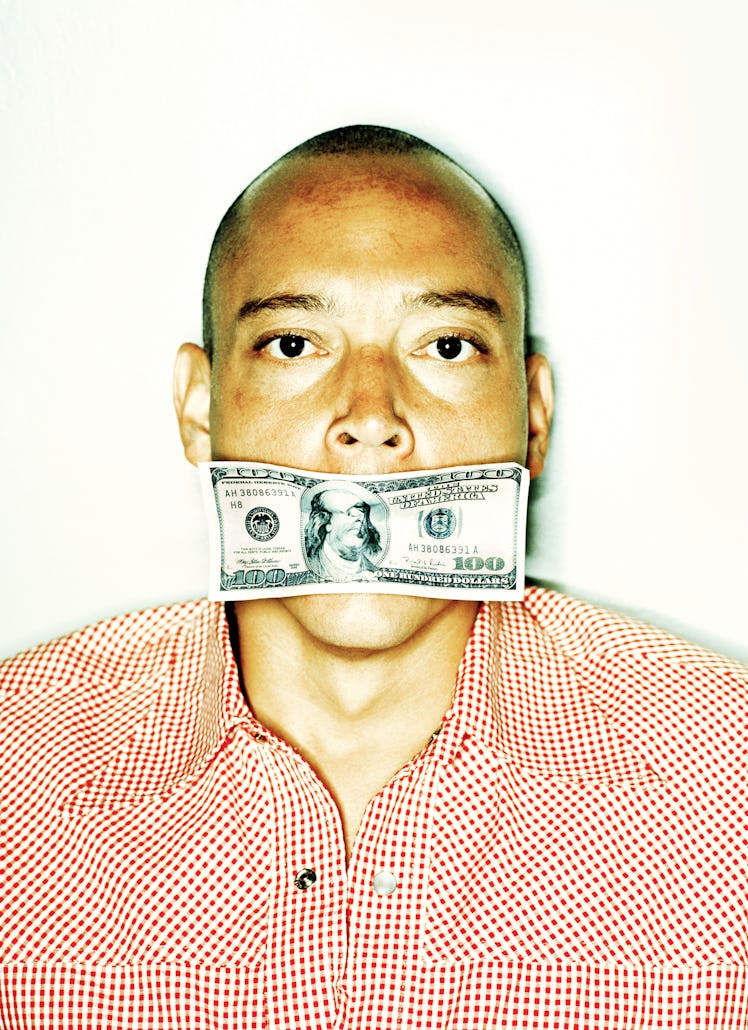 Portrait of man with hundred dollar bill covering his mouth.