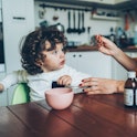 A mother gives her child a spoonful of cold and flu medicine.