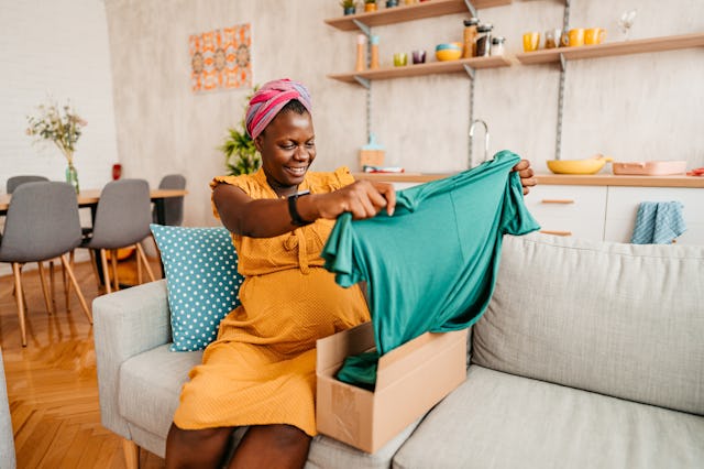A pregnant woman looks at a new dress.