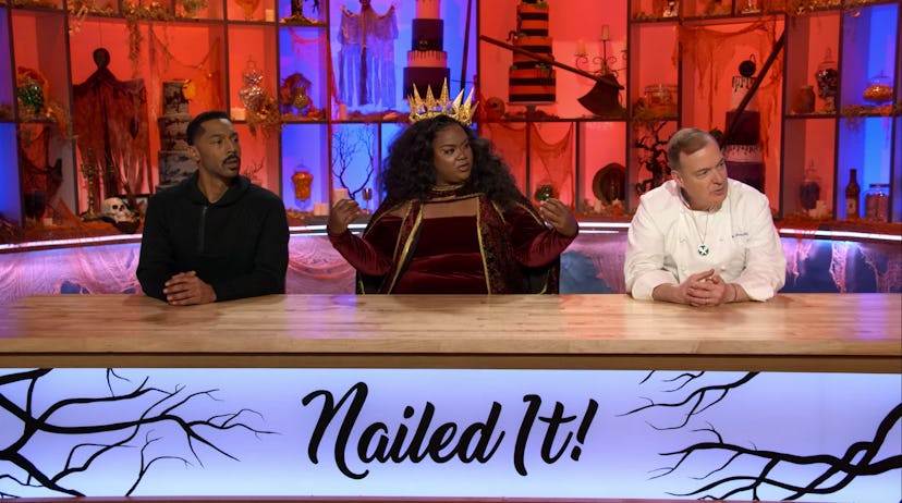 'Nailed It' judges sit behind the judging table, all decked out for Halloween