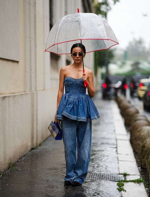 MILAN, ITALY - SEPTEMBER 21: Yoyo Cao wears sunglasses, a blue denim low-neck off-shoulder ruffled t...