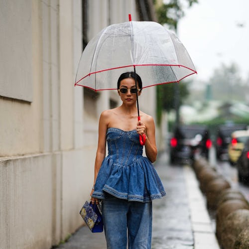 MILAN, ITALY - SEPTEMBER 21: Yoyo Cao wears sunglasses, a blue denim low-neck off-shoulder ruffled t...