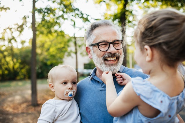An older dad plays with his two young kids.