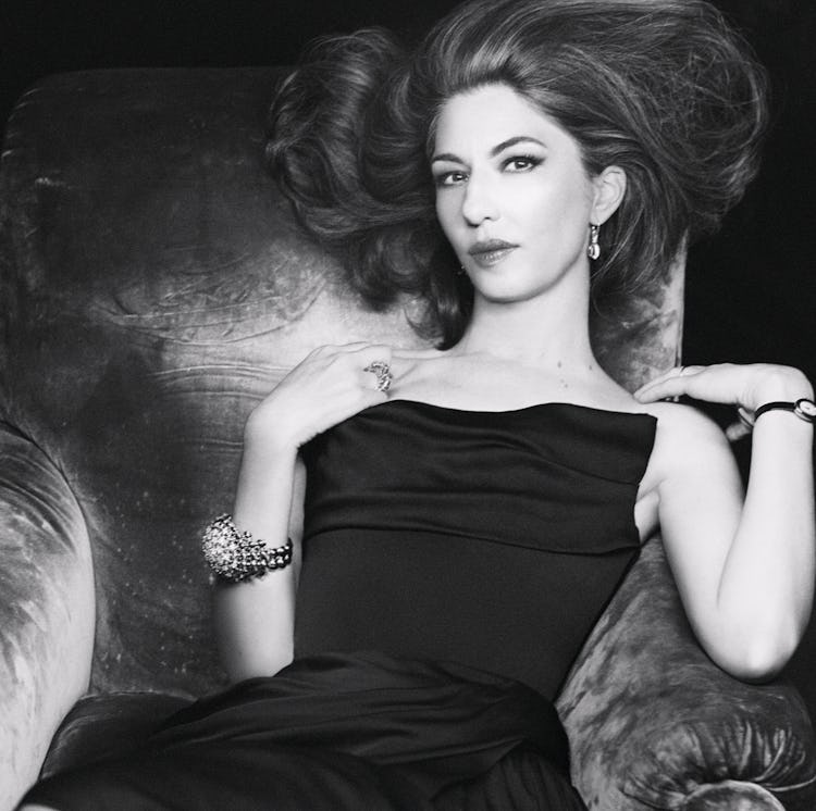 Movie director Sofia Coppola wears a black silk dress, watch, gaudy bracelet and rings.