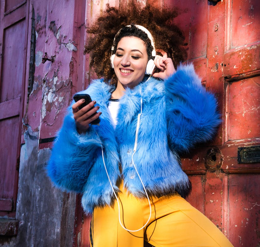 Young woman listening to music as one of the luckiest zodiac signs in October 2023.