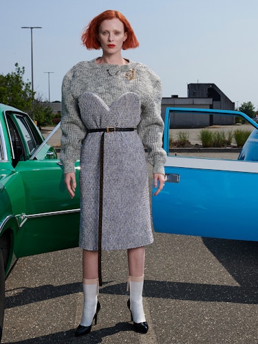 Model Karen Elson is wearing a gray knit sweater, grey sweater dress, thin leather belt, socks and s...