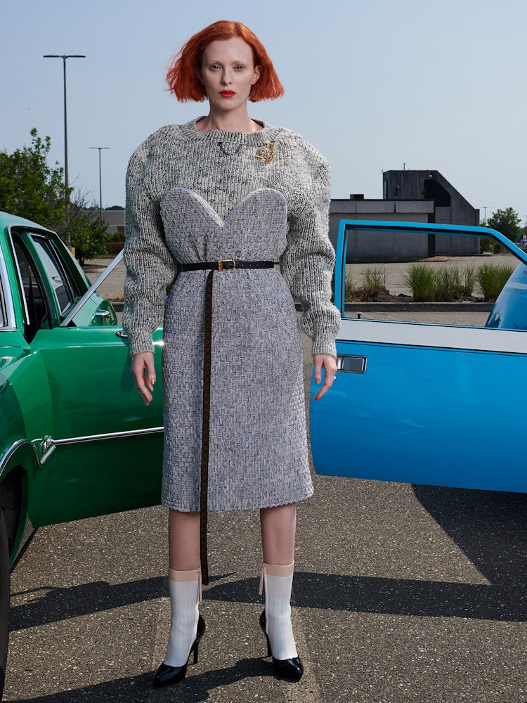 Model Karen Elson is wearing a gray knit sweater, grey sweater dress, thin leather belt, socks and s...
