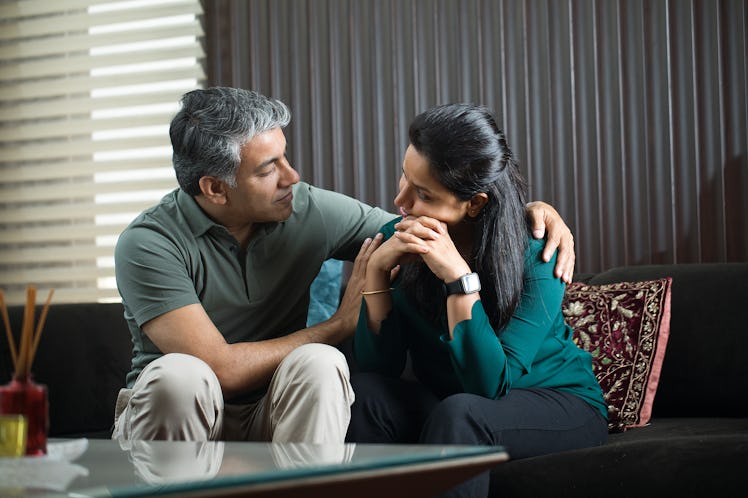 Middle aged husband and wife sitting on couch having serious discussion