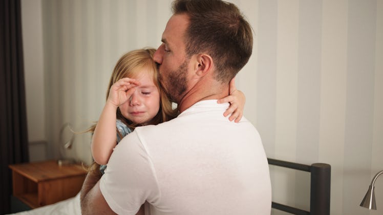 A dad practicing peaceful parenting, holding his child while they wipe away their tears.