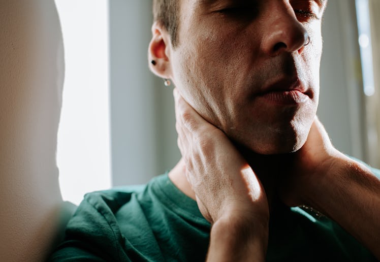 Close up of anxious man grabbing his neck.