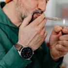 A middle-aged man lighting a joint.
