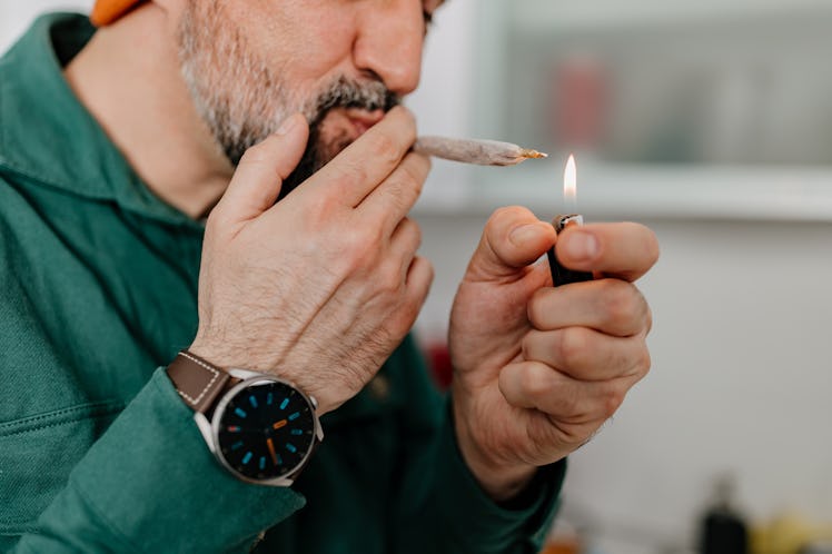 A middle-aged man lighting a joint.