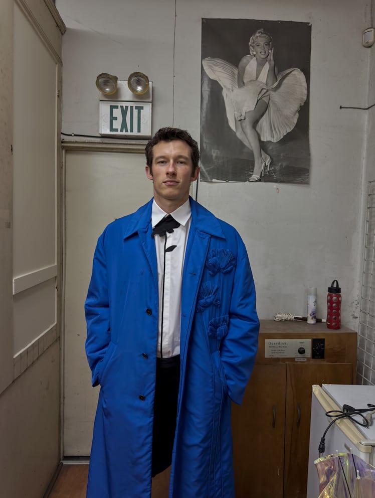 Callum Turner wears a Valentino coat, shirt, and pants.