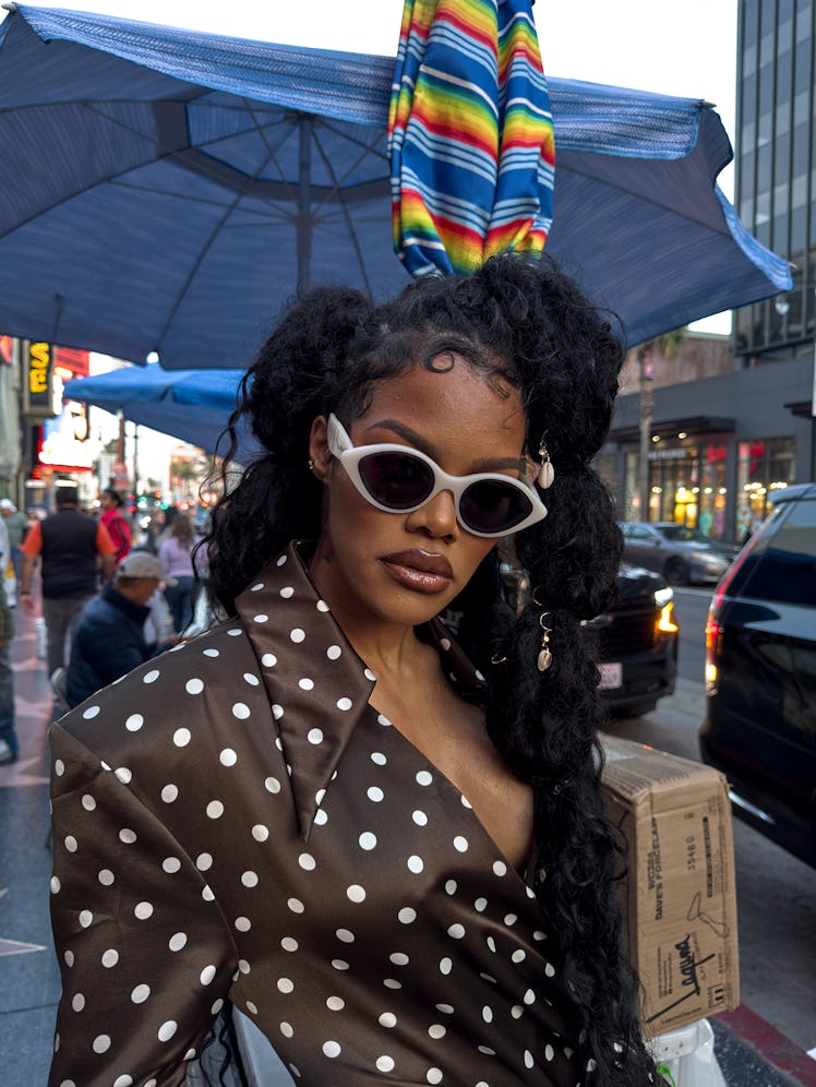 Teyana Taylor wears a brown and white polka dot shirt and sunglasses.
