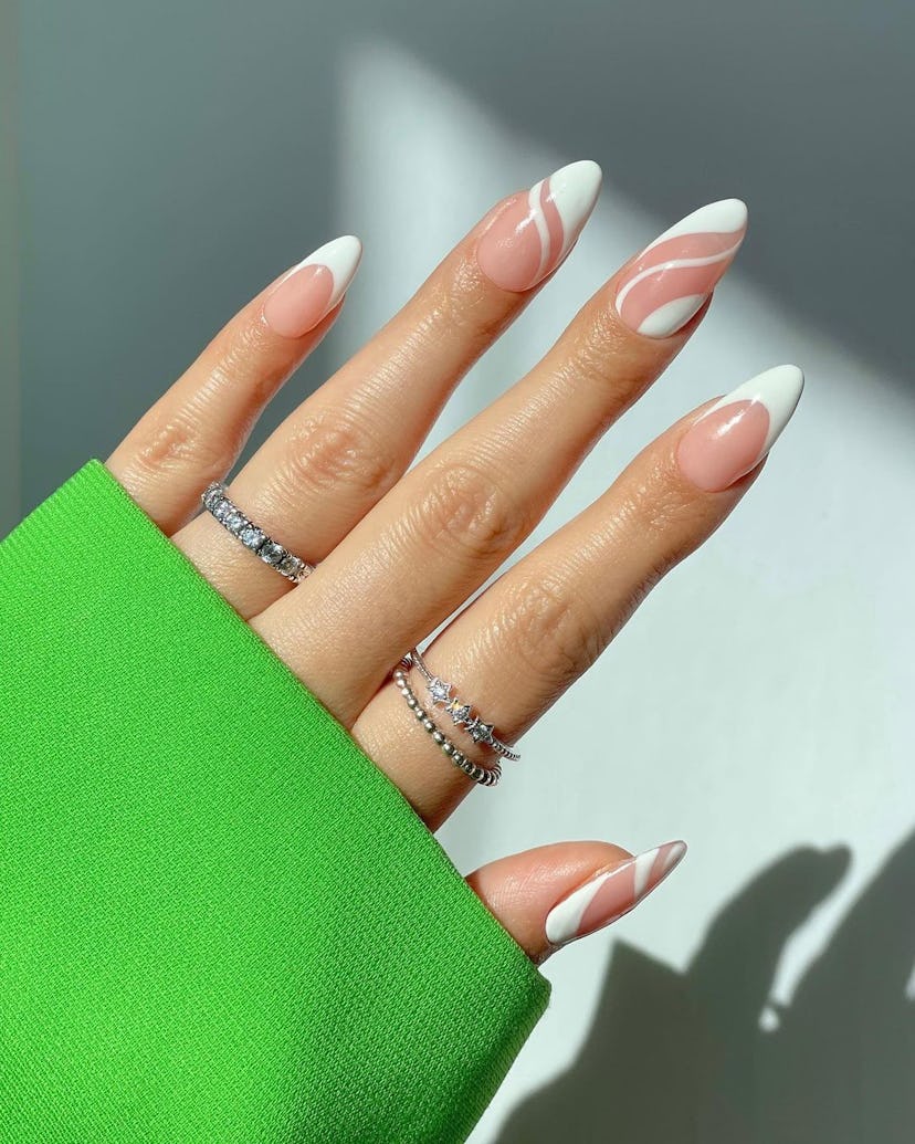 Abstract white French tip designs on short almond nails are on-trend for 2024.