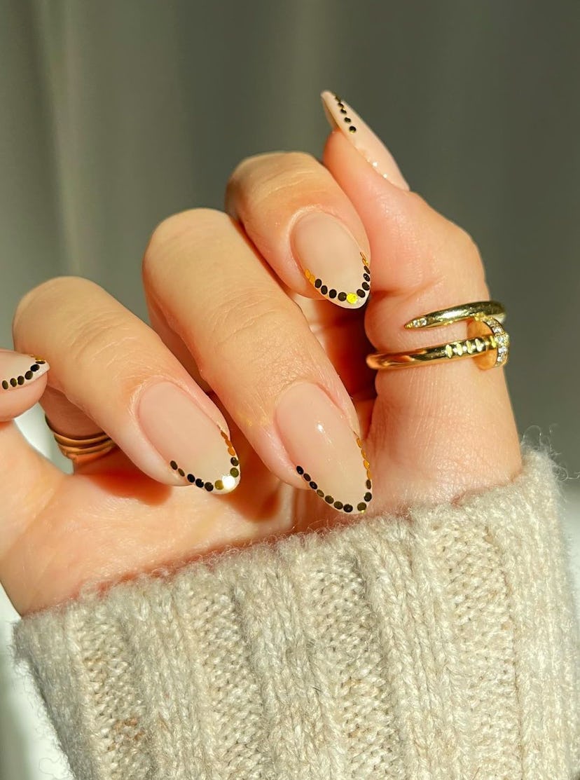 Gold sequin outlines on short almond nails are on-trend for 2024.