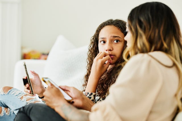 A teen and her mom look at their phones.