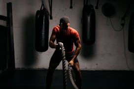 A man in a gym working out with ropes.