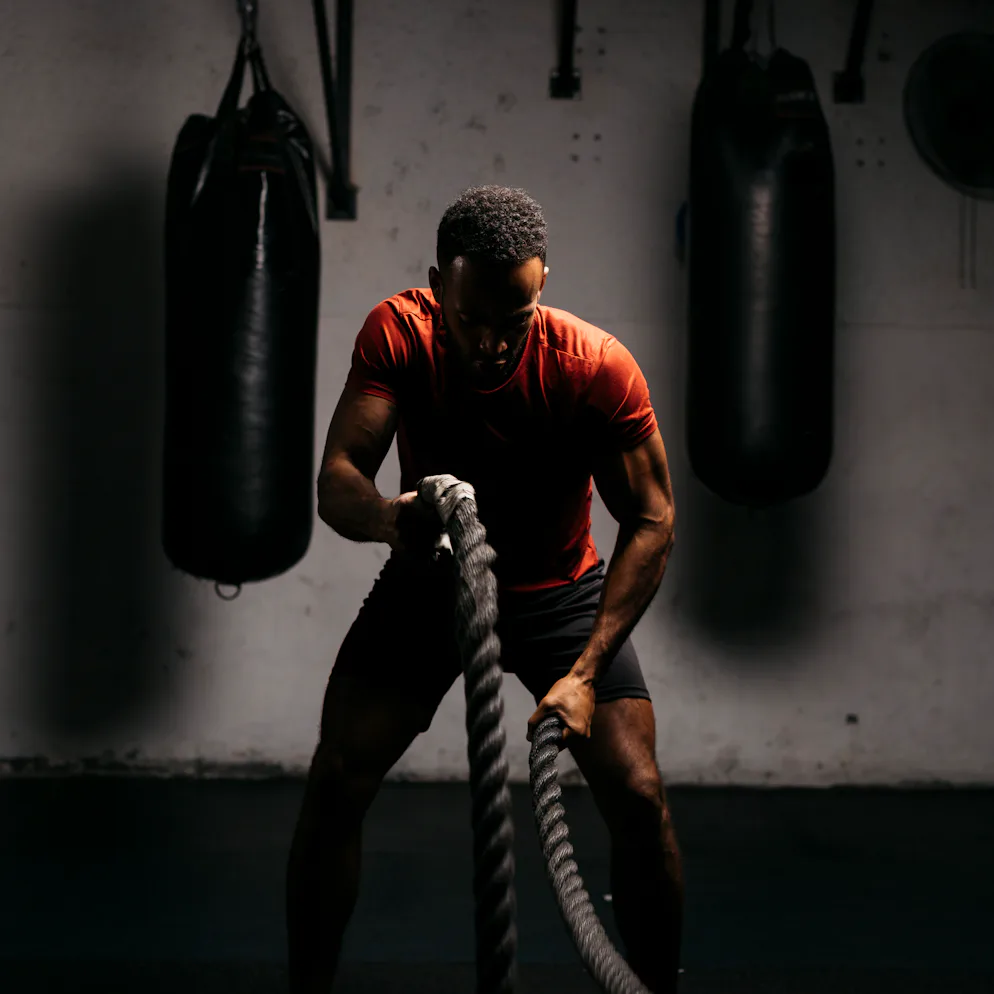 A man in a gym working out with ropes.