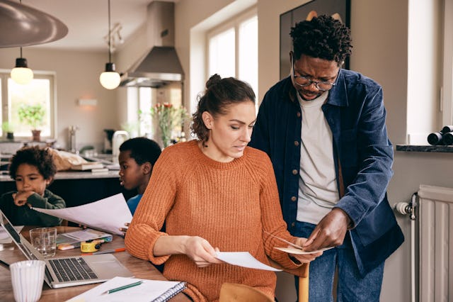 Parents go over their finances as their kids sit behind them.